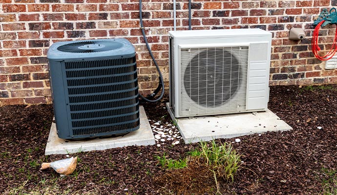 two outdoor air conditioning units placed on concrete slabs