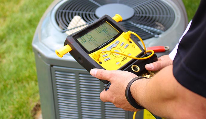 A person is peforming AC tune up service using a digital multimeter.