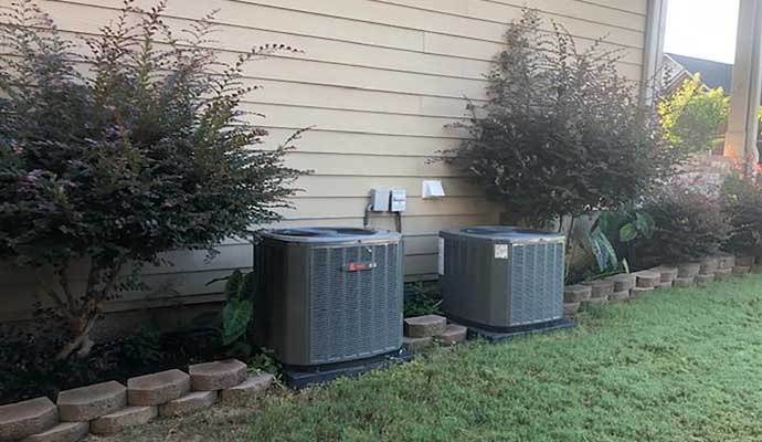 two large metal air conditioning units placed on a grassy area